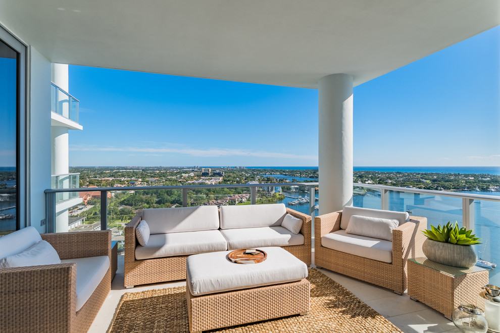This is an example of a beach style balcony in Miami with a roof extension and glass railing.