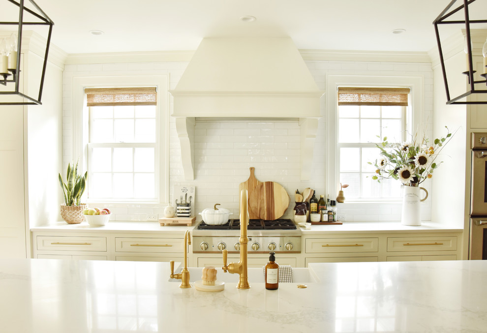 Design ideas for a traditional kitchen in Boston with a farmhouse sink, recessed-panel cabinets, quartz benchtops, white splashback, ceramic splashback, light hardwood floors, with island and white benchtop.