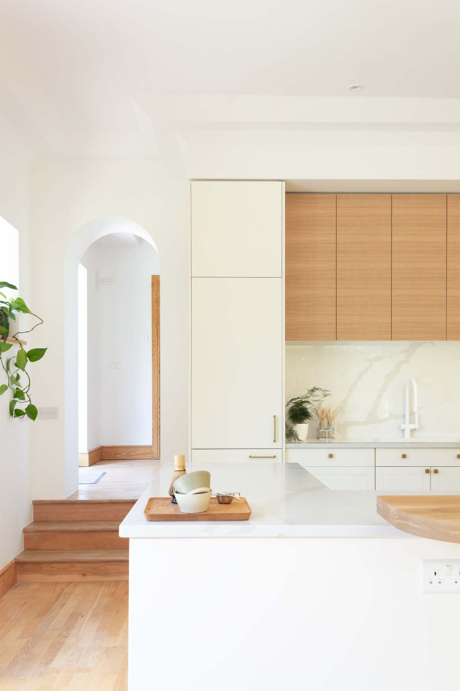 This is an example of a small contemporary u-shaped eat-in kitchen in Other with a single-bowl sink, shaker cabinets, white cabinets, quartzite benchtops, white splashback, stone slab splashback, white appliances, ceramic floors, with island, white floor and white benchtop.
