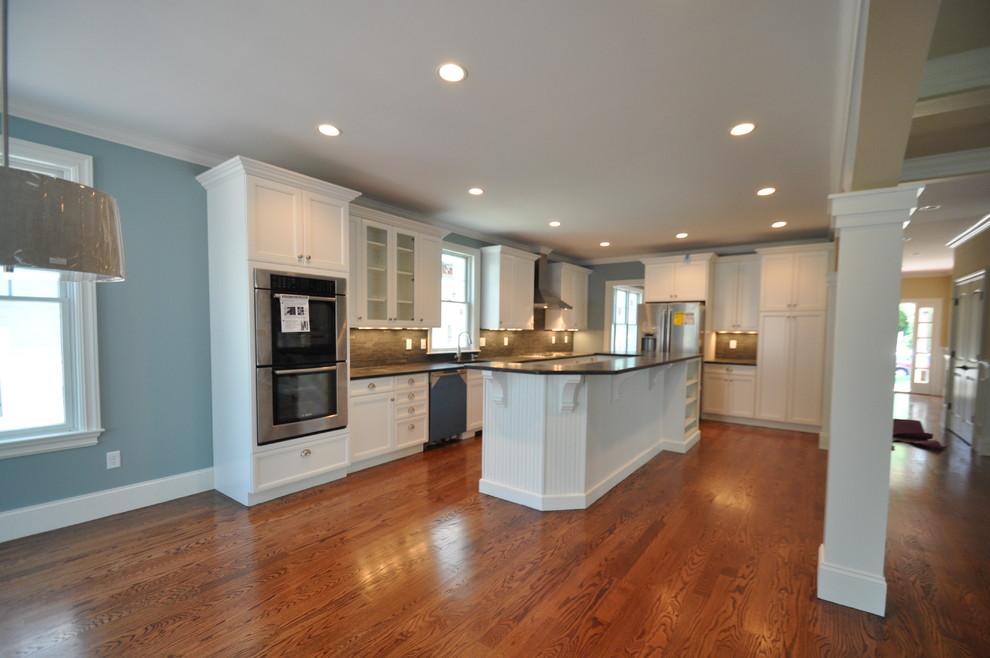 This is an example of a large traditional l-shaped open plan kitchen in Boston with an undermount sink, shaker cabinets, white cabinets, brown splashback, matchstick tile splashback, stainless steel appliances, medium hardwood floors, with island and blue floor.