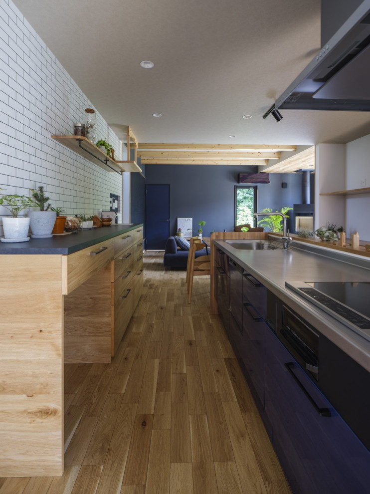 Пример оригинального дизайна: кухня-гостиная среднего размера в стиле модернизм с синими фасадами, столешницей из акрилового камня, белым фартуком, светлым паркетным полом, островом, коричневым полом, коричневой столешницей, потолком с обоями и обоями на стенах