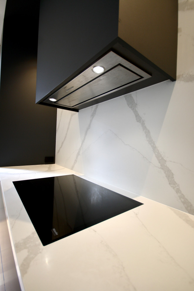Foto på ett stort funkis vit linjärt kök med öppen planlösning, med en undermonterad diskho, släta luckor, grå skåp, bänkskiva i kvarts, vitt stänkskydd, svarta vitvaror, mellanmörkt trägolv, en köksö och brunt golv