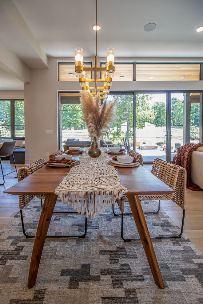 Inspiration for an expansive transitional open plan dining in Cleveland with beige walls, light hardwood floors, a standard fireplace, brown floor and recessed.