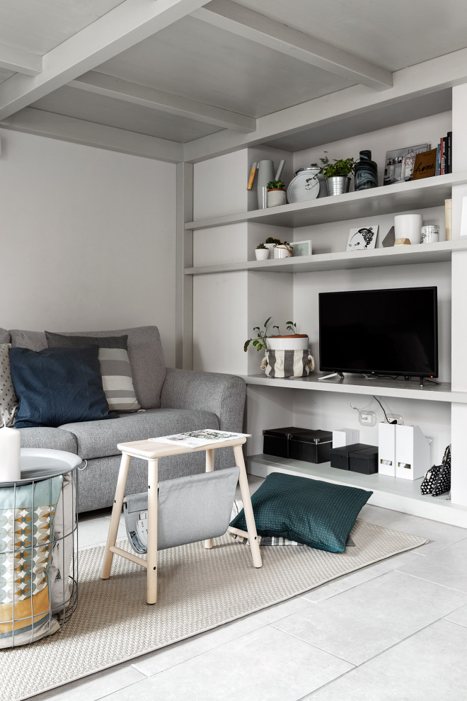 This is an example of a small scandinavian loft-style living room in Milan with a library, grey walls, porcelain floors and a freestanding tv.
