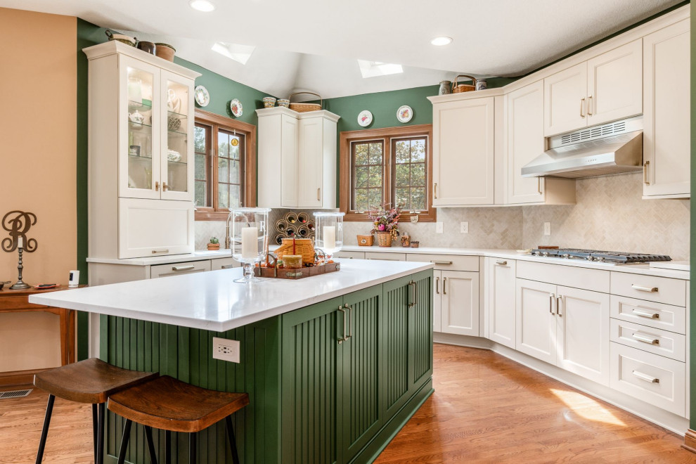 Inspiration for a transitional u-shaped medium tone wood floor and brown floor eat-in kitchen remodel in Columbus with a farmhouse sink, recessed-panel cabinets, white cabinets, quartzite countertops, beige backsplash, mosaic tile backsplash, stainless steel appliances, an island and white countertops