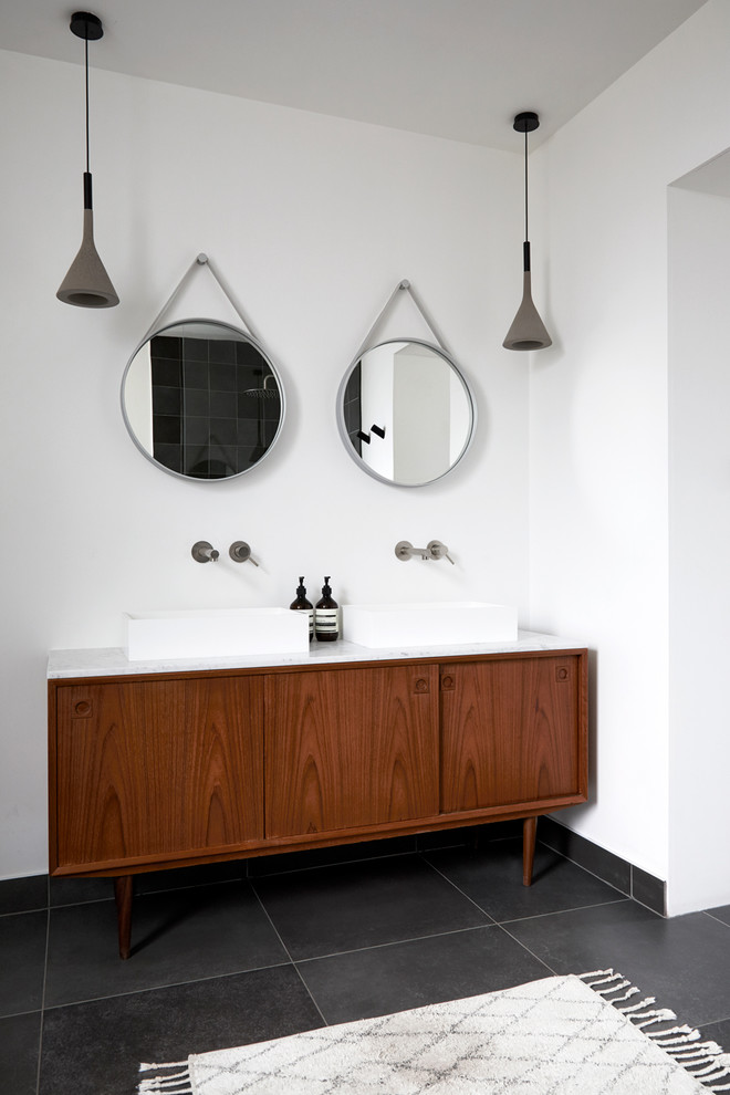 Large scandinavian ensuite bathroom in London with a freestanding bath, a walk-in shower, white walls, ceramic flooring, a vessel sink, marble worktops, black floors, an open shower, white worktops, flat-panel cabinets and brown cabinets.