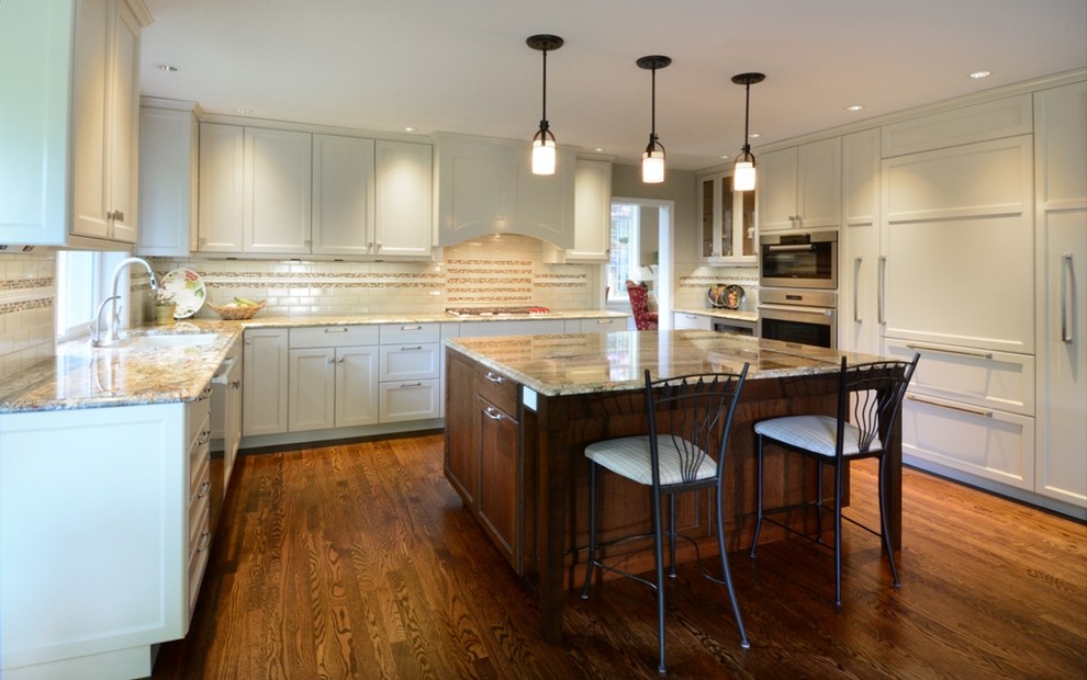 Large transitional l-shaped medium tone wood floor open concept kitchen photo in Seattle with a single-bowl sink, recessed-panel cabinets, white cabinets, granite countertops, beige backsplash, ceramic backsplash, stainless steel appliances and an island