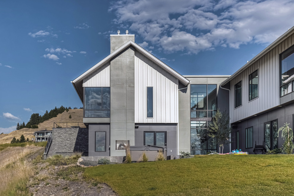 Foto della villa grande bianca contemporanea a due piani con rivestimenti misti, tetto a capanna, copertura a scandole, tetto grigio e pannelli e listelle di legno