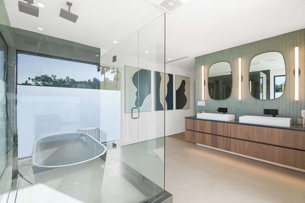 Design ideas for a large contemporary master wet room bathroom in Los Angeles with flat-panel cabinets, medium wood cabinets, a freestanding tub, porcelain floors, engineered quartz benchtops, a hinged shower door, brown benchtops, green tile, white walls, a trough sink, beige floor and a double vanity.