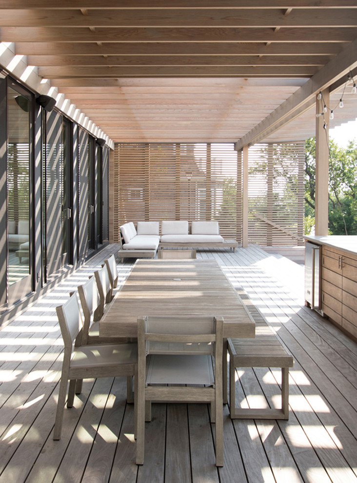 This is an example of a scandinavian deck in New York with an outdoor kitchen and a pergola.