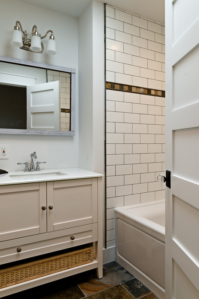 Inspiration for a mid-sized arts and crafts 3/4 bathroom in New York with furniture-like cabinets, white cabinets, an alcove tub, a shower/bathtub combo, subway tile, white walls, slate floors, an undermount sink, solid surface benchtops, multi-coloured floor and a hinged shower door.