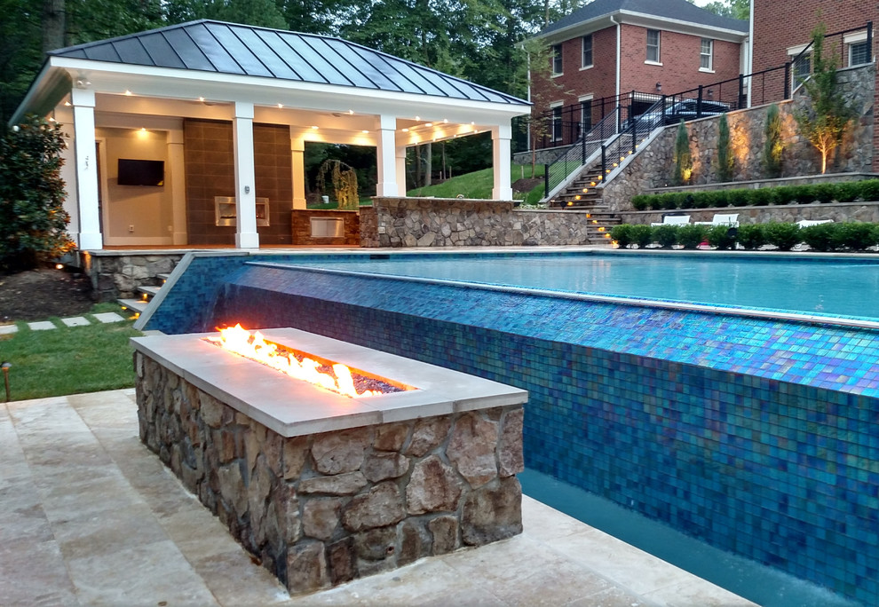 Inspiration for an expansive modern backyard rectangular infinity pool in DC Metro with a pool house and natural stone pavers.