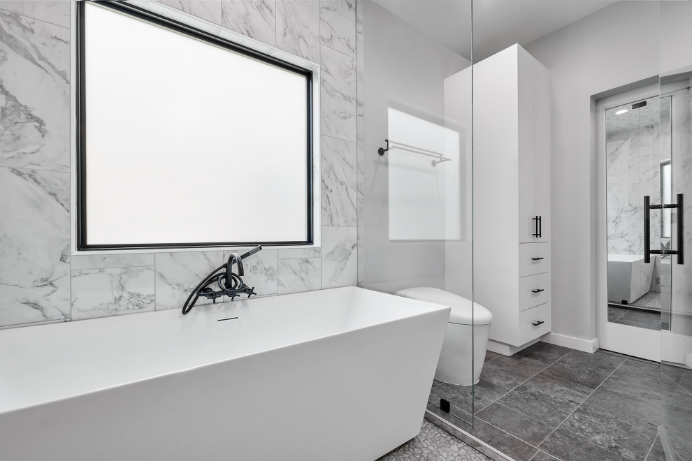 Пример оригинального дизайна: главная ванная комната среднего размера в стиле модернизм с плоскими фасадами, белыми фасадами, отдельно стоящей ванной, душевой комнатой, инсталляцией, белой плиткой, керамогранитной плиткой, белыми стенами, полом из керамогранита, настольной раковиной, столешницей из кварцита, серым полом, открытым душем, черной столешницей, нишей, тумбой под две раковины и встроенной тумбой