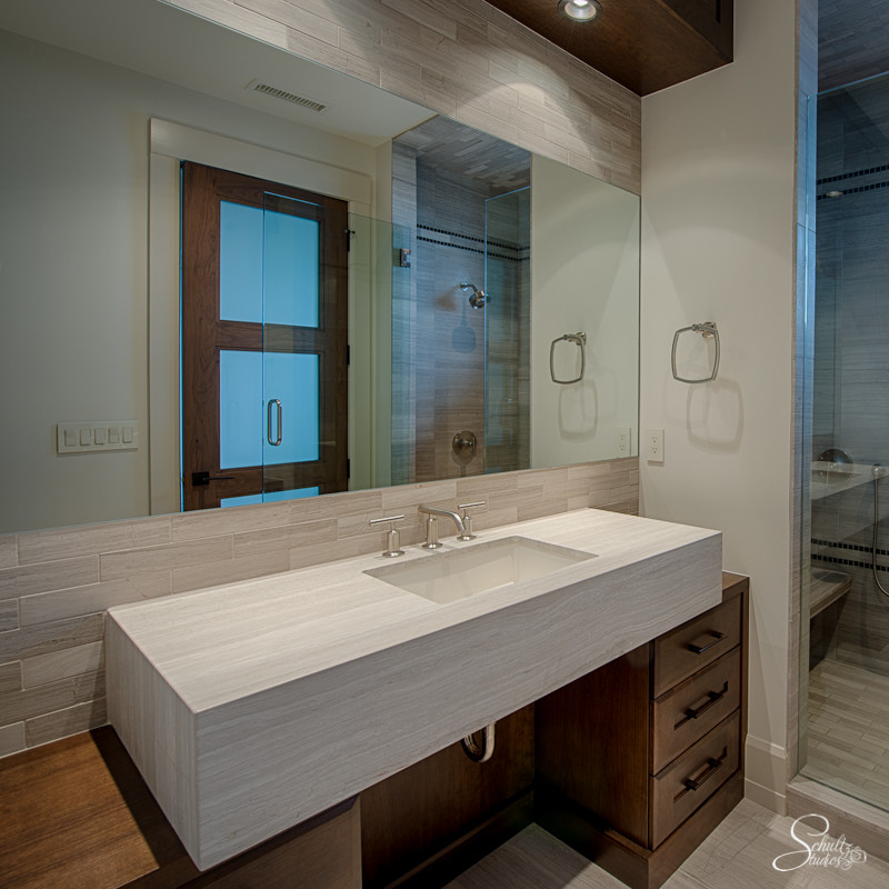 Photo of a mid-sized contemporary 3/4 bathroom in Other with flat-panel cabinets, dark wood cabinets, an alcove shower, beige tile, stone tile, white walls, ceramic floors and a drop-in sink.