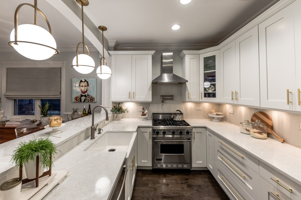 Example of a mid-sized transitional u-shaped dark wood floor and brown floor eat-in kitchen design in Chicago with a farmhouse sink, shaker cabinets, white cabinets, quartz countertops, gray backsplash, glass tile backsplash, stainless steel appliances, a peninsula and gray countertops