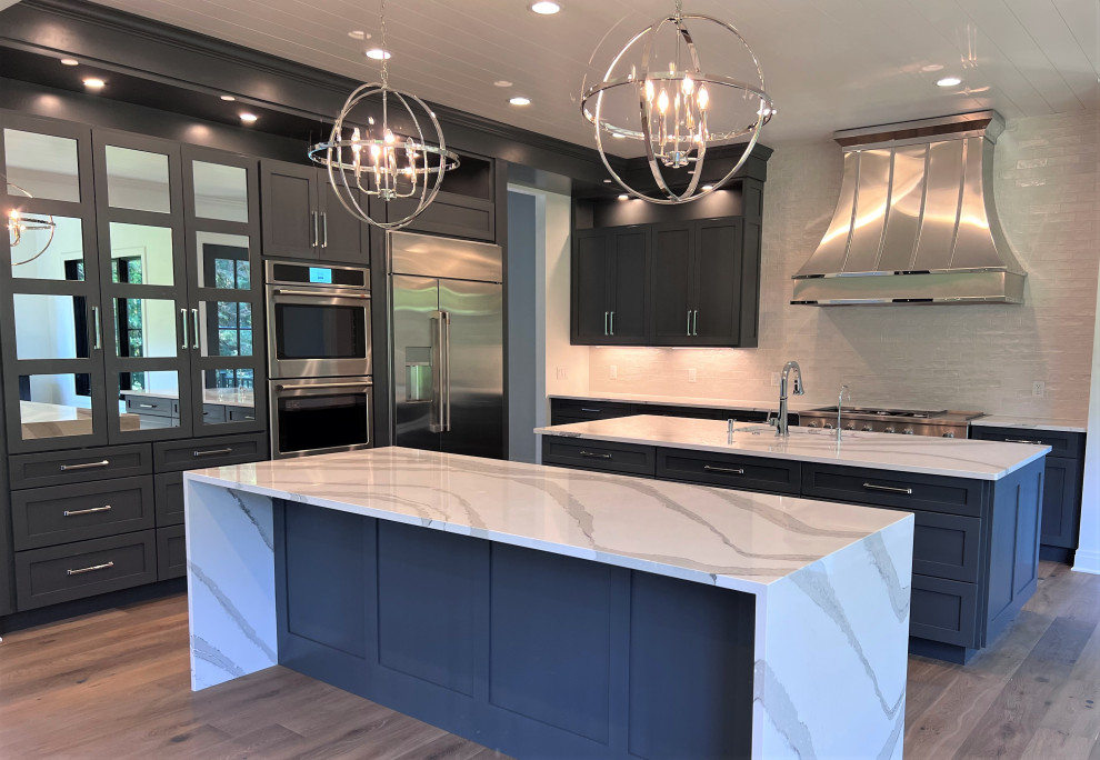 Inspiration for a large transitional kitchen remodel with an undermount sink, shaker cabinets, gray cabinets, quartz countertops, white backsplash, stainless steel appliances, two islands and white countertops