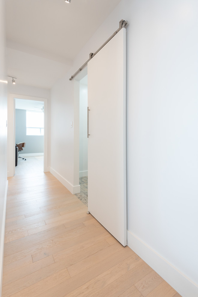 This is an example of a mid-sized contemporary hallway in Toronto with white walls, light hardwood floors and beige floor.