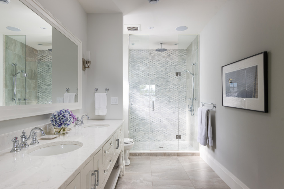 Photo of a beach style bathroom in Other with shaker cabinets, white cabinets, an alcove shower, white tile, grey walls, an undermount sink, grey floor, a hinged shower door, white benchtops, a double vanity and a freestanding vanity.
