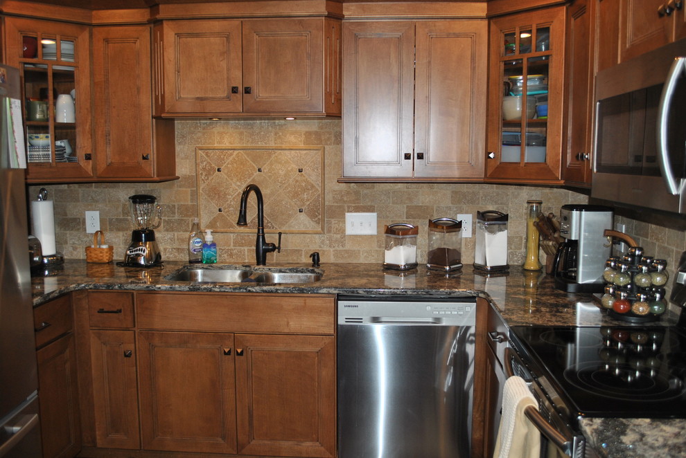 Brown floor kitchen photo with brown cabinets, beige backsplash, stainless steel appliances, an island and gray countertops