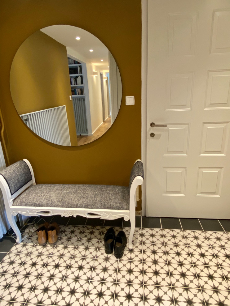 This is an example of an eclectic foyer in Grenoble with yellow walls, ceramic flooring, a single front door and a metal front door.