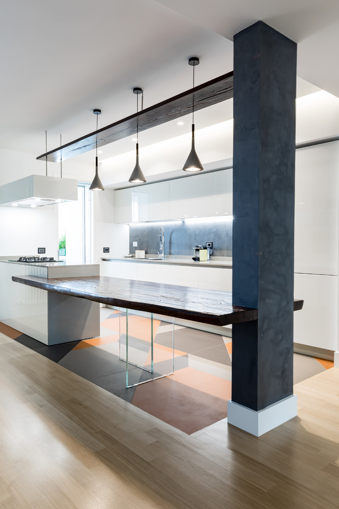 Photo of a contemporary galley open plan kitchen in Rome with white cabinets, grey splashback, a peninsula, grey benchtop, a drop-in sink, flat-panel cabinets, wood benchtops and multi-coloured floor.