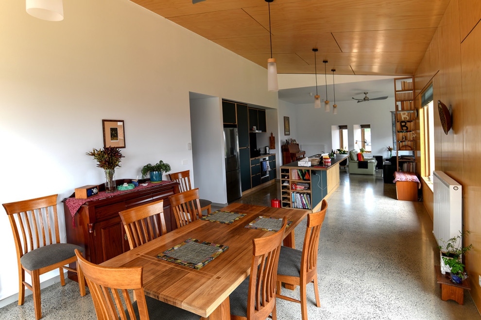 На фото: кухня-столовая среднего размера в стиле модернизм с бетонным полом, серым полом, потолком из вагонки и панелями на части стены с