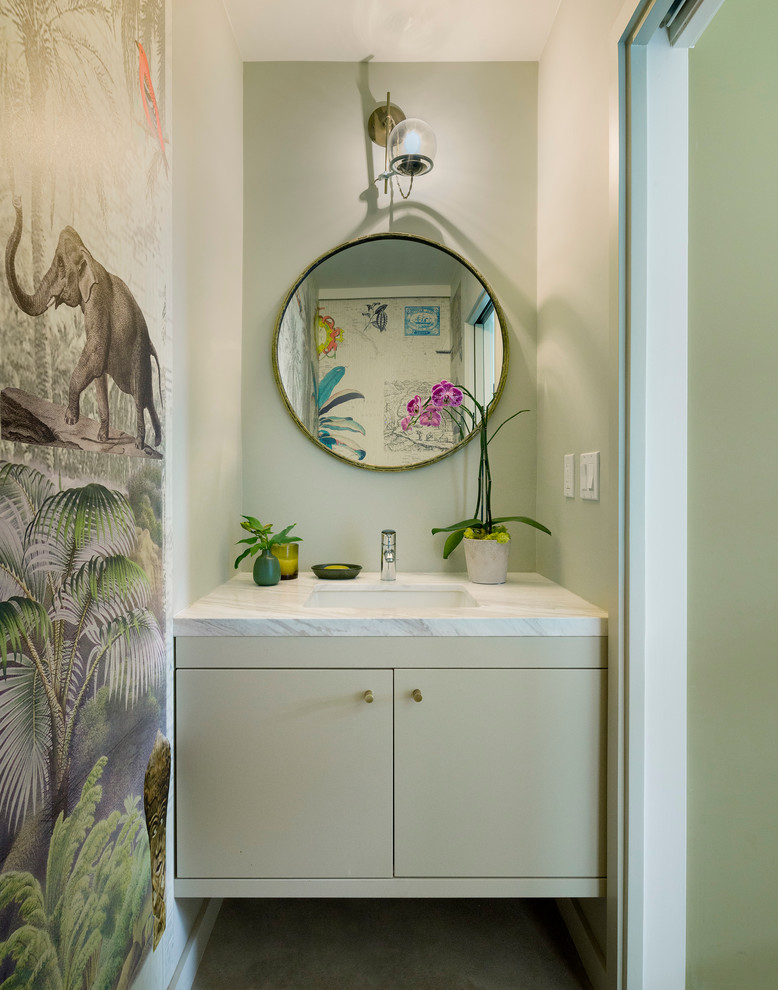 Small contemporary powder room in Los Angeles with an undermount sink, flat-panel cabinets, green cabinets, marble benchtops, concrete floors, beige walls and white benchtops.