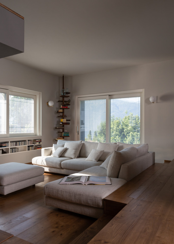 Esempio di un ampio soggiorno contemporaneo aperto con pareti bianche, pavimento in legno massello medio, TV a parete, pavimento beige e soffitto ribassato