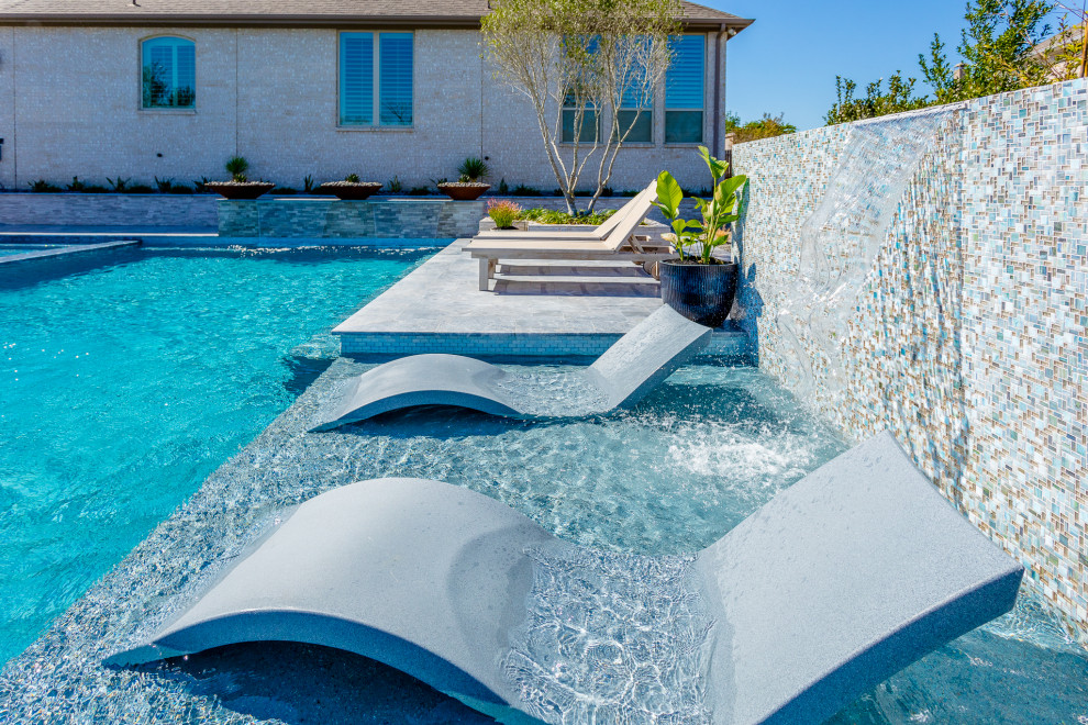 Idée de décoration pour une grande piscine à débordement et latérale bohème rectangle avec des pavés en pierre naturelle.