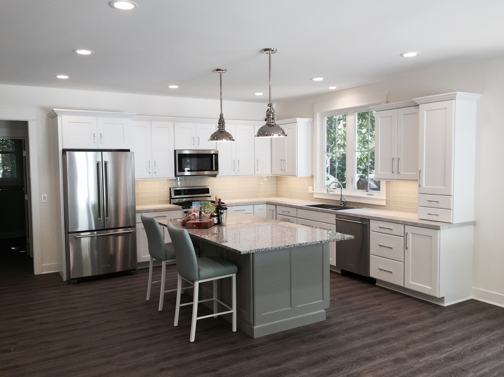 Example of a mid-sized transitional l-shaped dark wood floor open concept kitchen design in Grand Rapids with a double-bowl sink, recessed-panel cabinets, white cabinets, quartzite countertops, green backsplash, subway tile backsplash, stainless steel appliances and an island