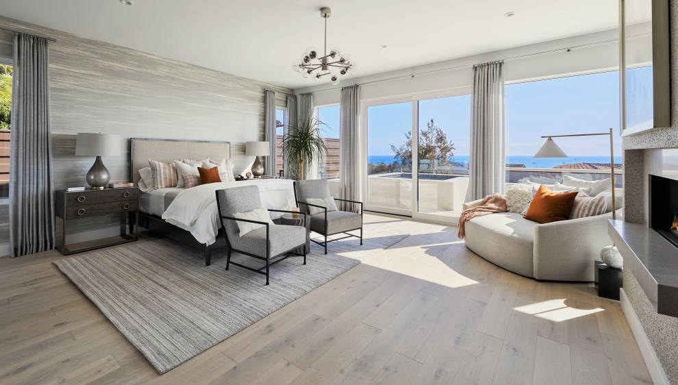 Großes Modernes Hauptschlafzimmer mit weißer Wandfarbe, braunem Holzboden, Kamin und Tapetenwänden in Orange County