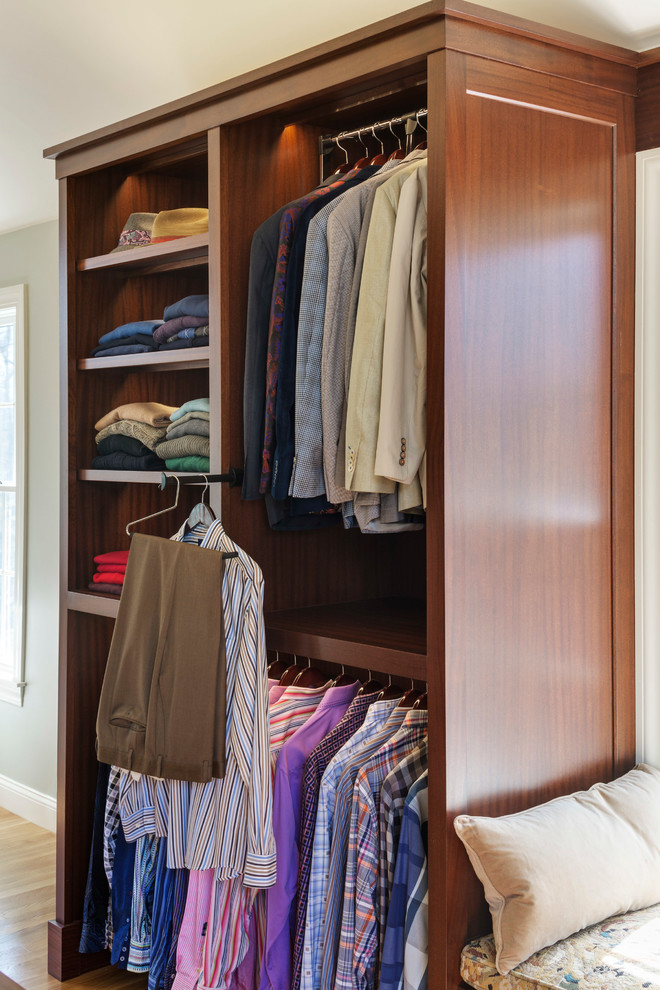 Photo of a traditional gender neutral walk-in wardrobe in Boston with dark wood cabinets and medium hardwood flooring.