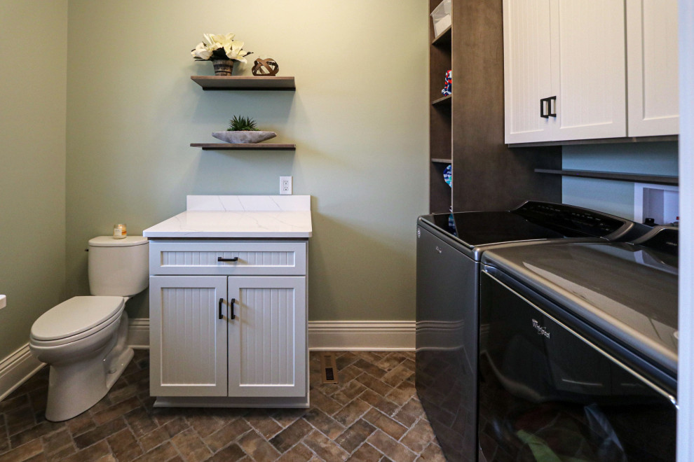 Small transitional l-shaped utility room in Cleveland with an undermount sink, flat-panel cabinets, white cabinets, quartz benchtops, green walls, porcelain floors, a side-by-side washer and dryer, brown floor and white benchtop.