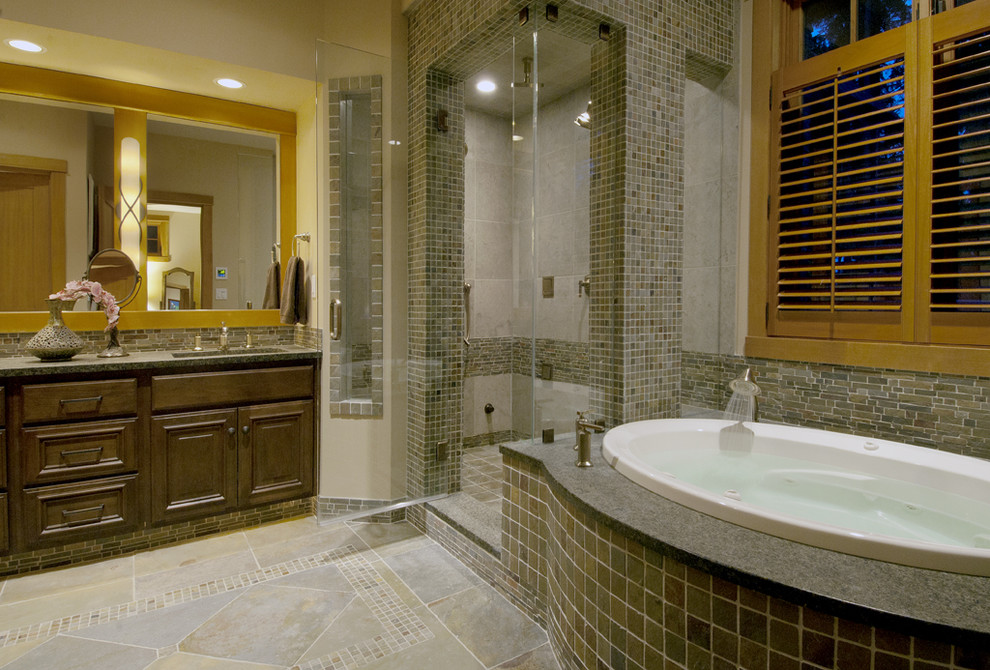 Photo of a large contemporary master bathroom in Seattle with raised-panel cabinets, dark wood cabinets, a drop-in tub, a corner shower, beige tile, brown tile, gray tile, multi-coloured tile, stone tile, beige walls, mosaic tile floors, an undermount sink and granite benchtops.