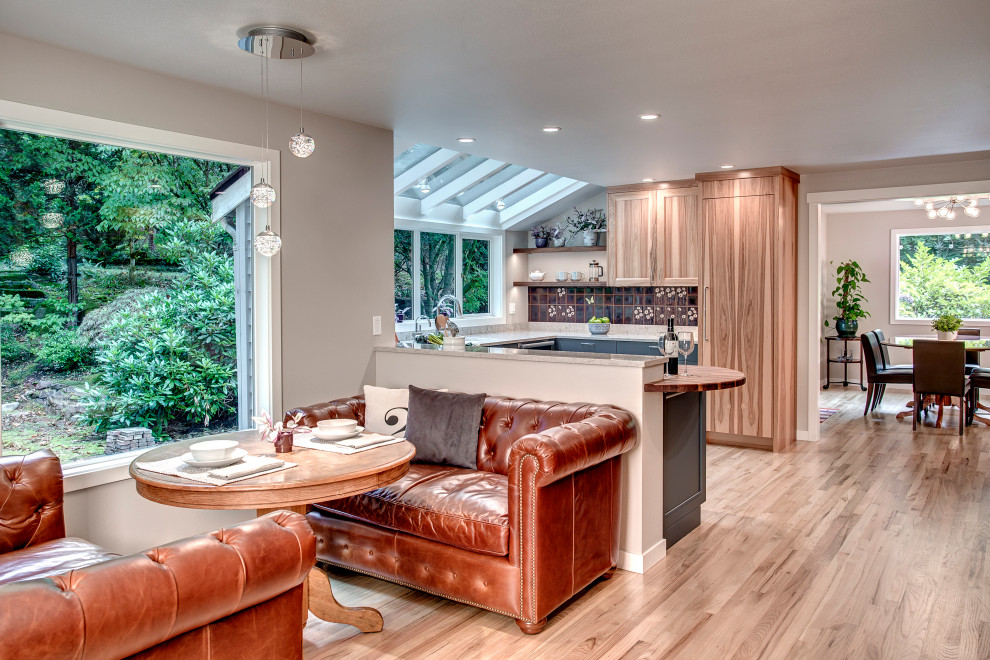 Photo of a large eclectic u-shaped open plan kitchen in Seattle with a single-bowl sink, flat-panel cabinets, blue cabinets, quartz benchtops, multi-coloured splashback, ceramic splashback, stainless steel appliances, light hardwood floors, a peninsula, brown floor and grey benchtop.