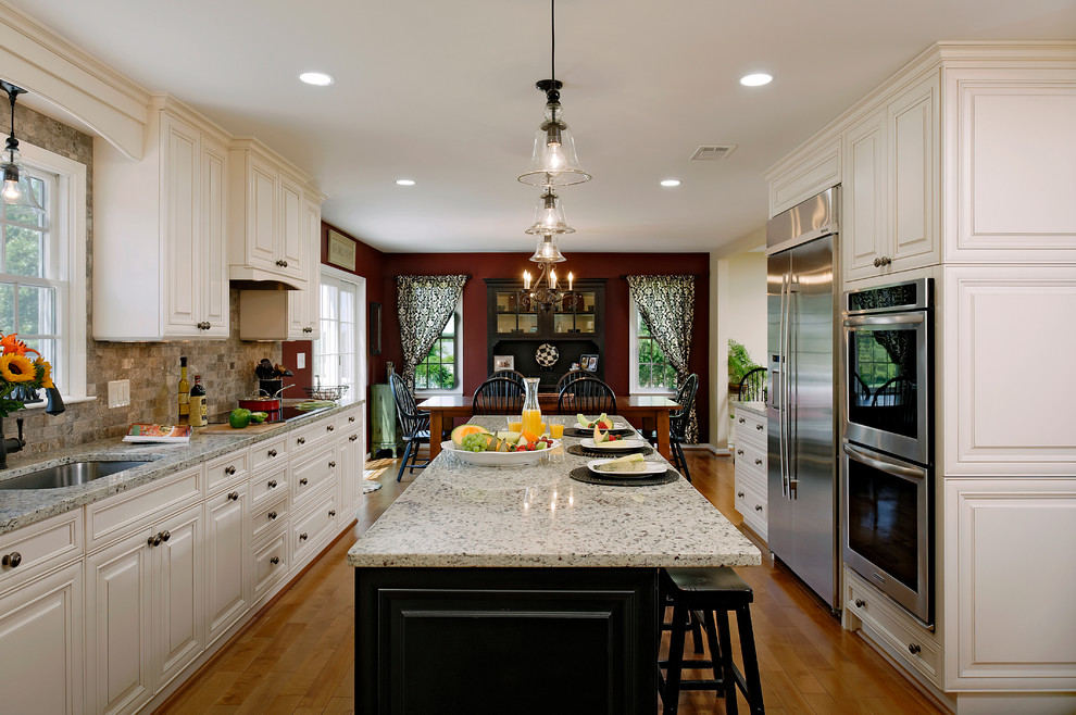This is an example of a large traditional galley eat-in kitchen in DC Metro with stainless steel appliances, an undermount sink, raised-panel cabinets, white cabinets, granite benchtops, multi-coloured splashback, stone tile splashback, with island, medium hardwood floors and brown floor.