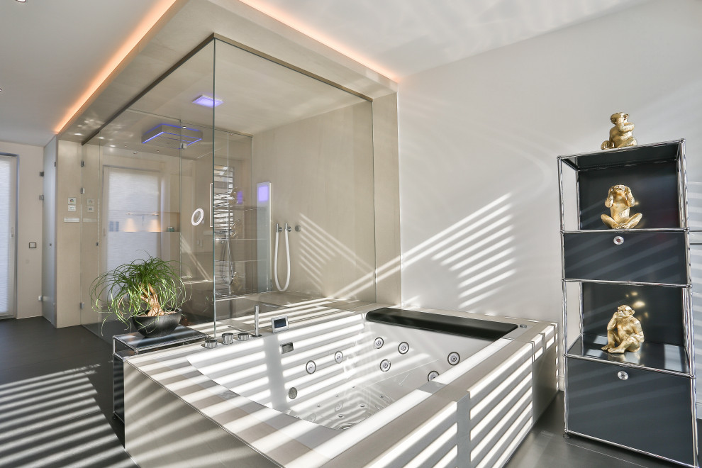 This is an example of a large contemporary master bathroom in Frankfurt with flat-panel cabinets, dark wood cabinets, a freestanding tub, a curbless shower, a wall-mount toilet, beige tile, stone tile, beige walls, slate floors, an integrated sink, glass benchtops, black floor, an open shower, grey benchtops, an enclosed toilet, a double vanity, a floating vanity, wallpaper and wallpaper.