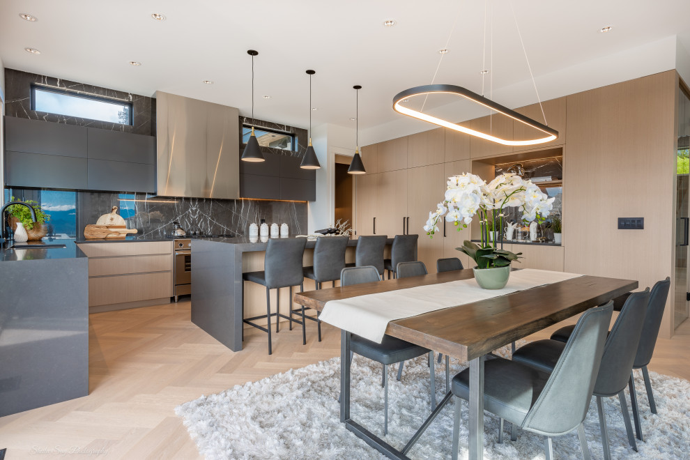 This is an example of a large contemporary eat-in kitchen in Vancouver with an undermount sink, flat-panel cabinets, light wood cabinets, quartz benchtops, black splashback, marble splashback, stainless steel appliances, light hardwood floors, with island and grey benchtop.
