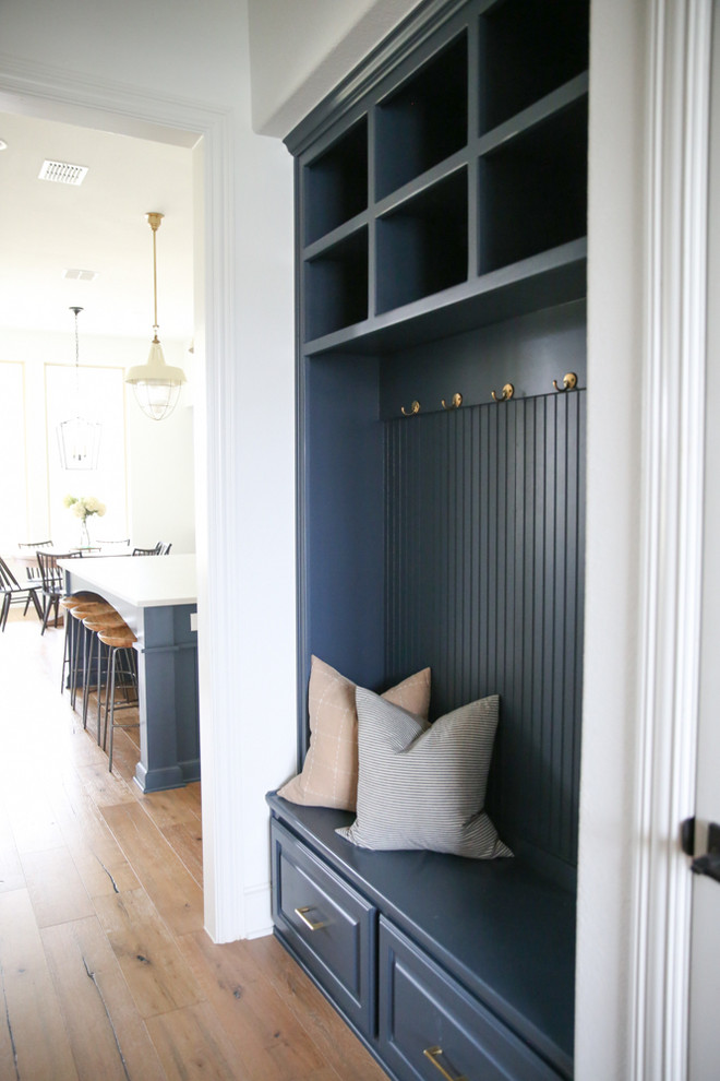 Inspiration for a mid-sized transitional medium tone wood floor and brown floor mudroom remodel in Dallas with white walls