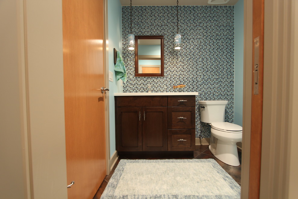 Inspiration for a mid-sized transitional 3/4 bathroom in Other with shaker cabinets, dark wood cabinets, an alcove shower, a two-piece toilet, blue tile, glass sheet wall, blue walls, concrete floors, an undermount sink and engineered quartz benchtops.