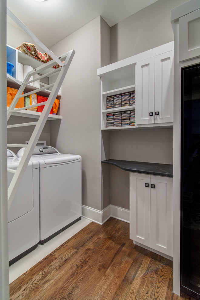 Small traditional l-shaped laundry room in Nashville with shaker cabinets, white cabinets, granite benchtops, grey walls, medium hardwood floors and a side-by-side washer and dryer.