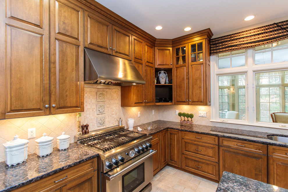 This is an example of an expansive traditional u-shaped open plan kitchen in Boston with a drop-in sink, raised-panel cabinets, medium wood cabinets, granite benchtops, beige splashback, ceramic splashback, stainless steel appliances, ceramic floors, with island and beige floor.