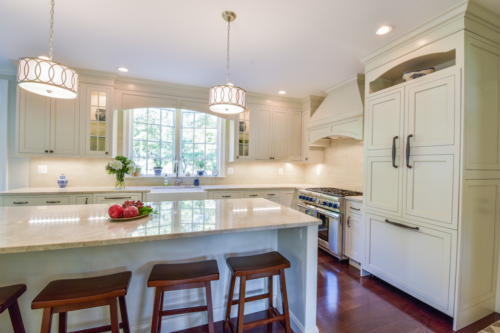 Photo of a large transitional l-shaped open plan kitchen in DC Metro with an undermount sink, beaded inset cabinets, white cabinets, quartz benchtops, beige splashback, subway tile splashback, stainless steel appliances, dark hardwood floors, with island and brown floor.