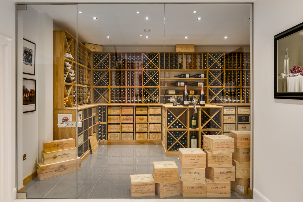 This is an example of an expansive contemporary wine cellar in London with grey floor, porcelain floors and storage racks.