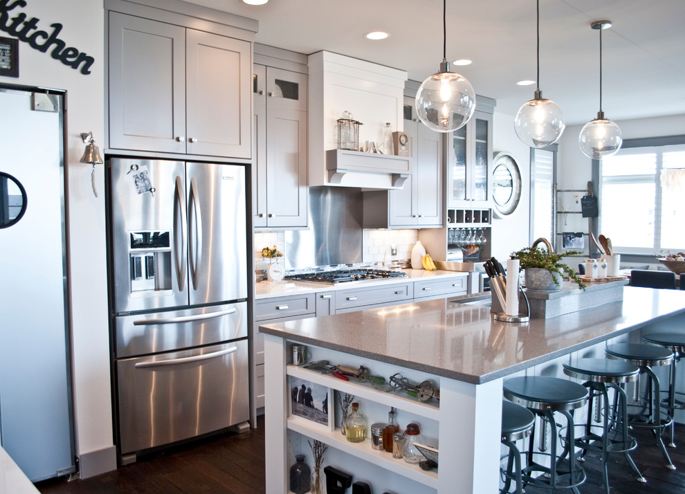 Inspiration for a large transitional l-shaped open concept kitchen remodel with an undermount sink, flat-panel cabinets, gray cabinets, quartzite countertops, white backsplash, subway tile backsplash, stainless steel appliances and an island