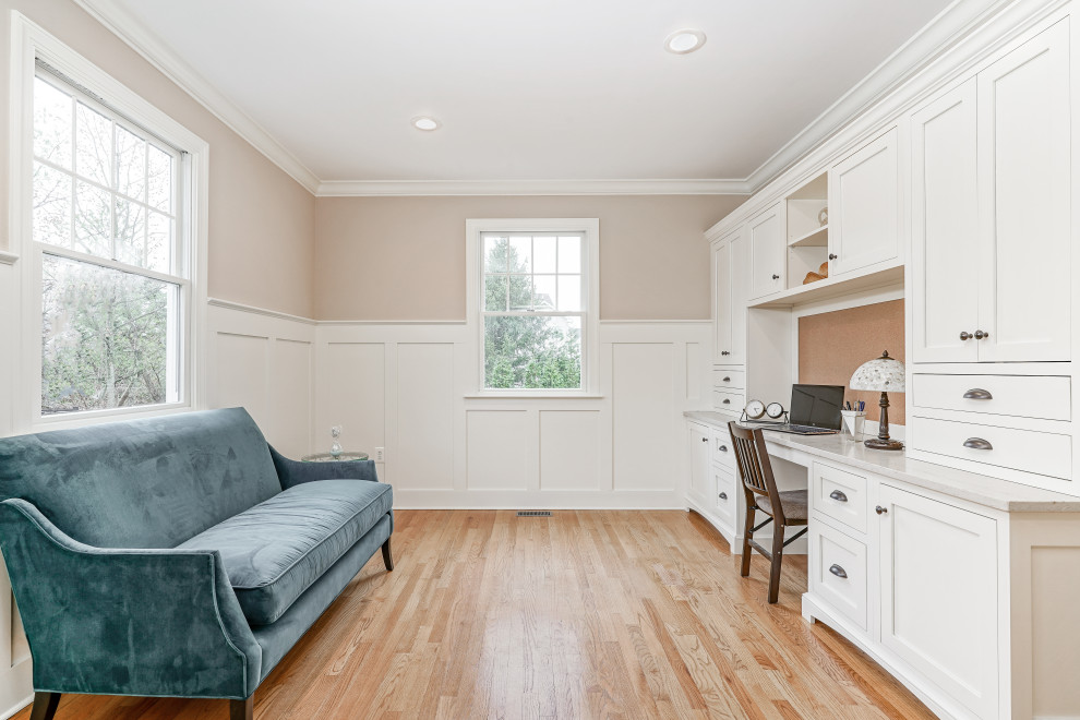 Klassisches Arbeitszimmer ohne Kamin mit beiger Wandfarbe, braunem Holzboden, Einbau-Schreibtisch, braunem Boden und Wandpaneelen in Philadelphia
