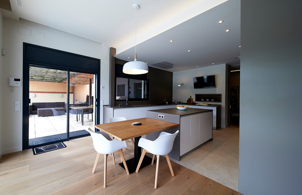Design ideas for a large modern l-shaped open plan kitchen in Barcelona with an undermount sink, flat-panel cabinets, brown cabinets, marble benchtops, brown splashback, marble splashback, black appliances, porcelain floors, with island, beige floor and brown benchtop.