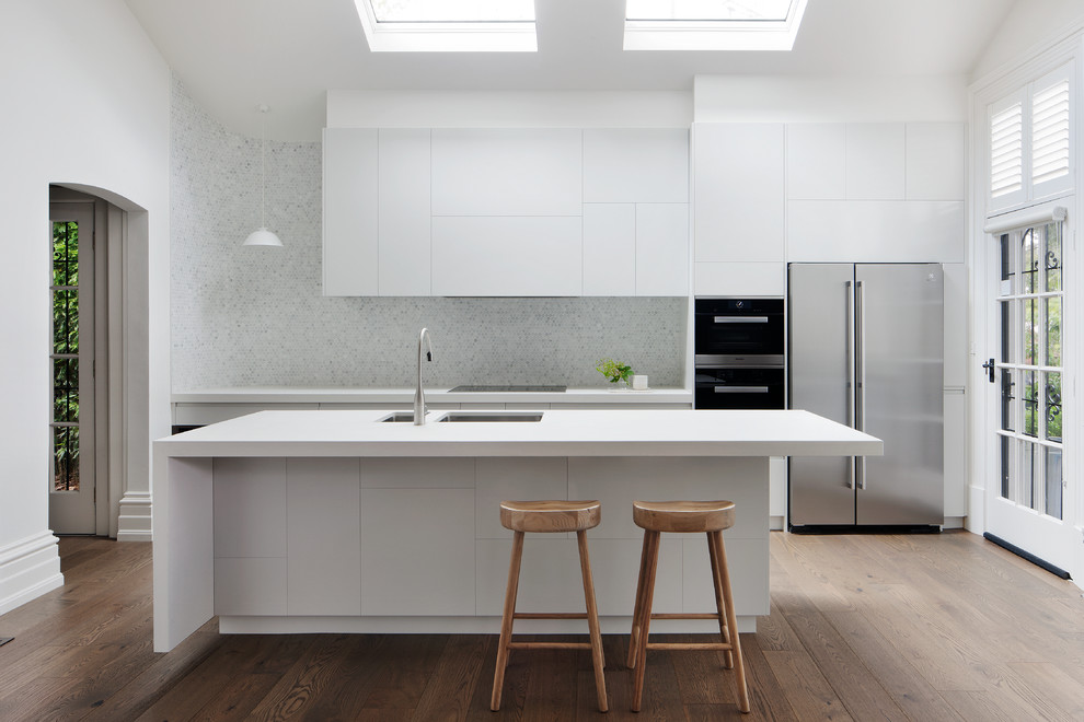 This is an example of a large contemporary single-wall kitchen pantry in Melbourne with a double-bowl sink, beaded inset cabinets, white cabinets, laminate benchtops, stone slab splashback, stainless steel appliances and with island.