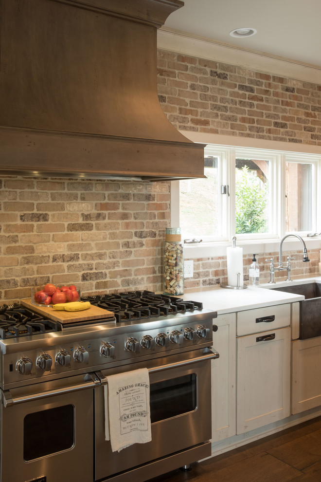 Open concept kitchen - large transitional galley dark wood floor and brown floor open concept kitchen idea with a farmhouse sink, shaker cabinets, quartz countertops, brown backsplash, brick backsplash, stainless steel appliances and an island