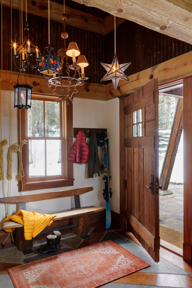 Example of a mid-sized mountain style concrete floor and gray floor mudroom design in Denver with white walls and a medium wood front door